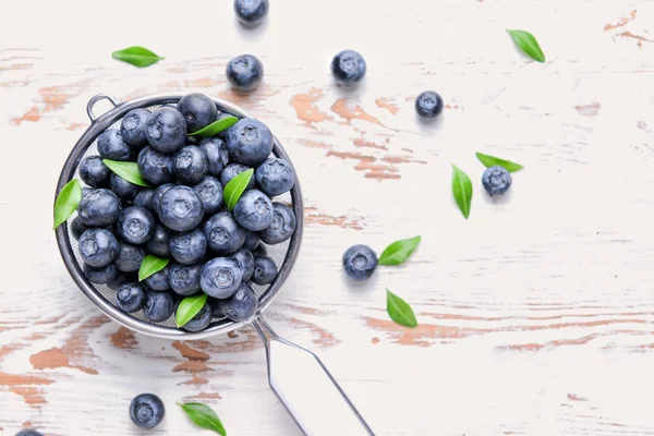 Zeef met rijpe Blueberry op lichte houten achtergrond — Stockfoto