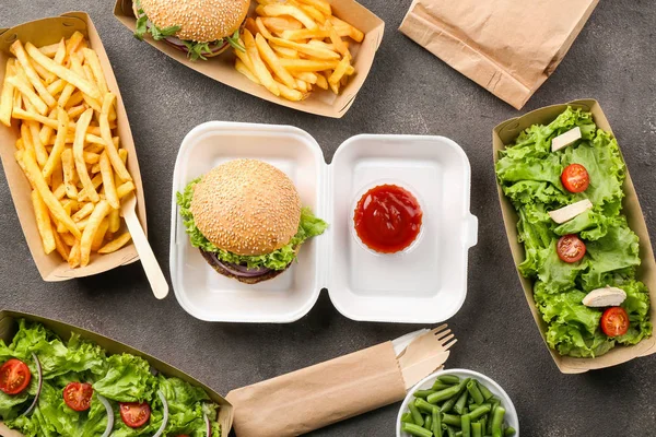 Containers with delicious food on grey background — Stock Photo, Image