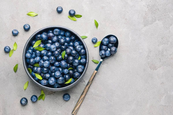 Kase ve kaşık gri arka plan üzerinde olgun yaban mersini ile