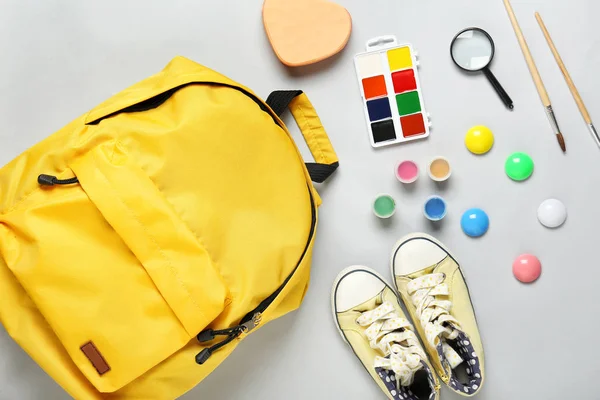 Mochila con útiles escolares y zapatos sobre fondo gris — Foto de Stock