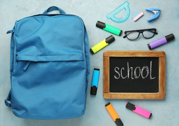 Mochila con fuentes y pizarra con palabra ESCUELA sobre fondo gris —  Fotos de Stock