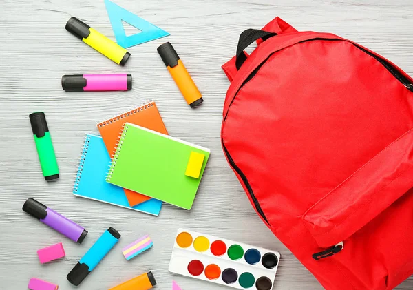 Mochila con útiles escolares sobre fondo de madera gris — Foto de Stock