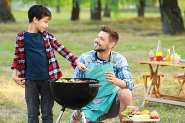 Baba barbekü ızgara açık havada lezzetli yemekler pişirme ile küçük çocuk
