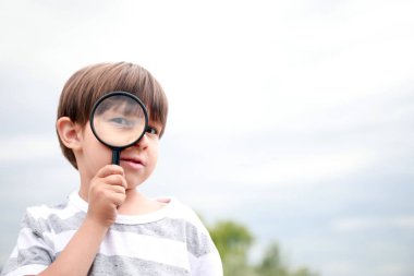 Doğayı dışarıda inceleyen büyüteçli küçük çocuk