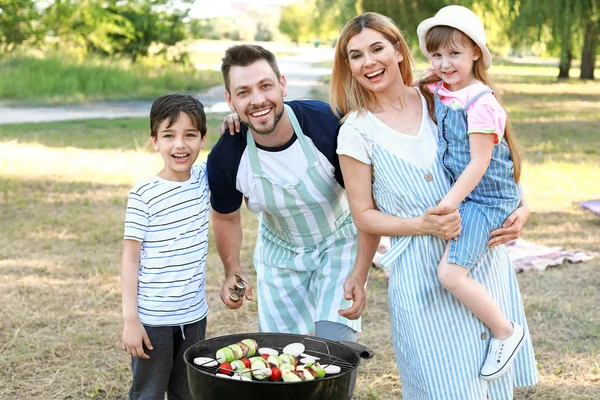 Happy family cooking tasty food on barbecue grill outdoors — Stock Photo, Image