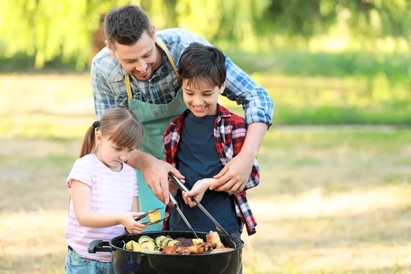 Little children with father cooking tasty food on barbecue grill outdoors — Stock Photo, Image