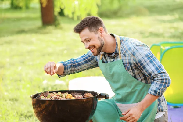 Man cooking tasty food on barbecue grill outdoors — Stock Photo, Image