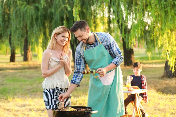 Happy pár vaří chutné jídlo na grilu venku — Stock fotografie