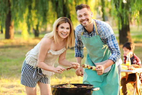 Happy couple cooking tasty food on barbecue grill outdoors — Stock Photo, Image