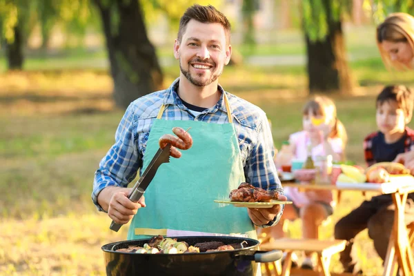 Man cooking tasty food on barbecue grill outdoors — Stock Photo, Image