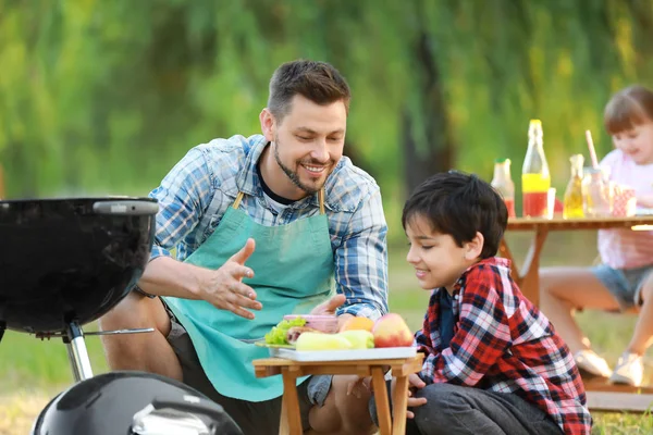 Kleiner Junge mit Vater kocht leckeres Essen auf Grill im Freien — Stockfoto