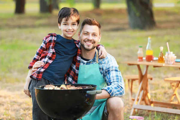 Mały chłopiec z ojcem gotowanie smaczne jedzenie na grilla Grill na zewnątrz — Zdjęcie stockowe