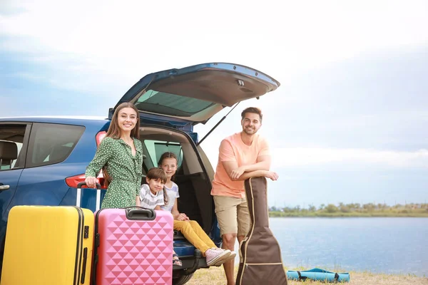 Happy family with luggage near car at resort — Stock Photo, Image