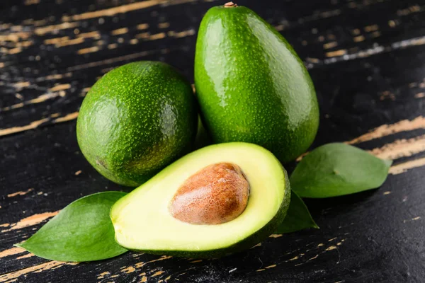 Aguacates maduros frescos sobre fondo de madera oscura —  Fotos de Stock