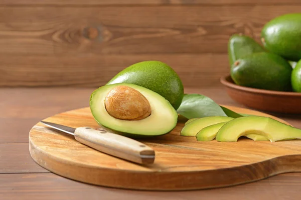 Свежие спелые авокадо с ножом на доске — стоковое фото