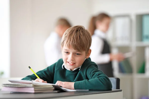 Schattige kleine school jongen doet lessen in het klaslokaal — Stockfoto