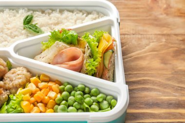 Ahşap masada lezzetli yemek ile Okul öğle yemeği kutusu