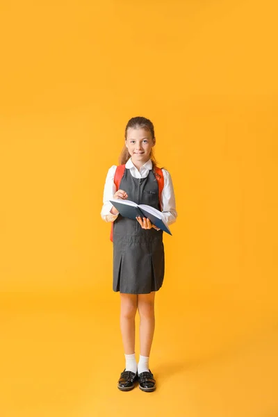 Schattig klein schoolmeisje op kleur achtergrond — Stockfoto