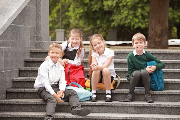 Cute little pupils sitting on stairs in park — Stock Photo, Image