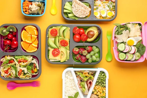 School lunch boxes with tasty food on color background