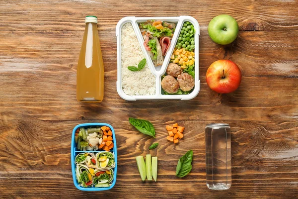 School lunchboxen met lekker eten en drinken op houten tafel — Stockfoto