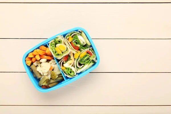 Σχολικό κουτί μεσημεριανού γεύματος με νόστιμο φαγητό σε λευκό ξύλινο φόντο — Φωτογραφία Αρχείου