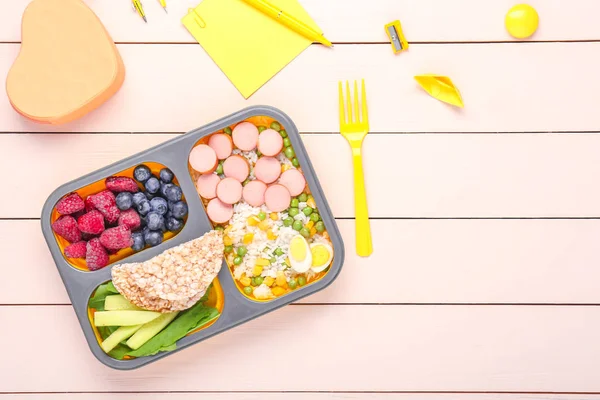 School lunch box with tasty food and stationery on table — Stock Photo, Image