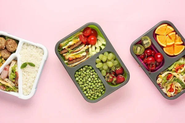 School lunch boxes with tasty food on color background — Stock Photo, Image