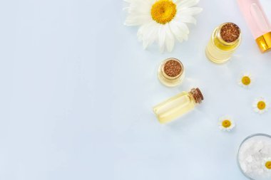 Beyaz arka planda papatya çiçekleri ile uçucu yağ Şişeleri