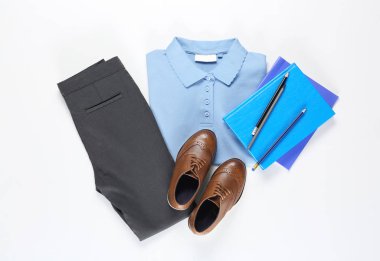 Beyaz arka planda kırtasiye malzemesi olan şık okul üniforması.