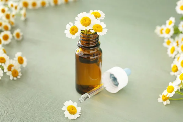 Bottle of essential oil with chamomile flowers on wooden table — Stock Photo, Image