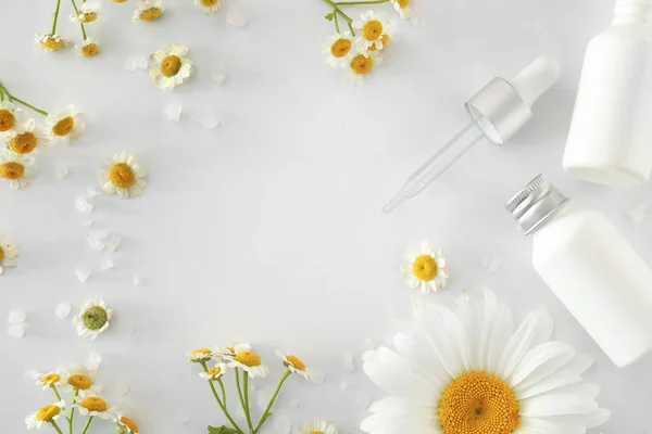 Frame made of cosmetic products with chamomile flowers on white background — Stock Photo, Image