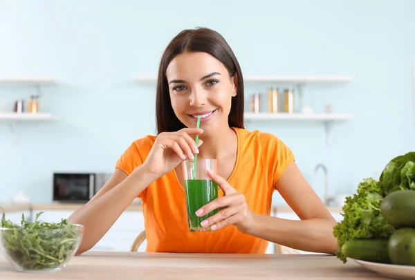 Jonge vrouw die gezond groente sap drinkt in de keuken — Stockfoto