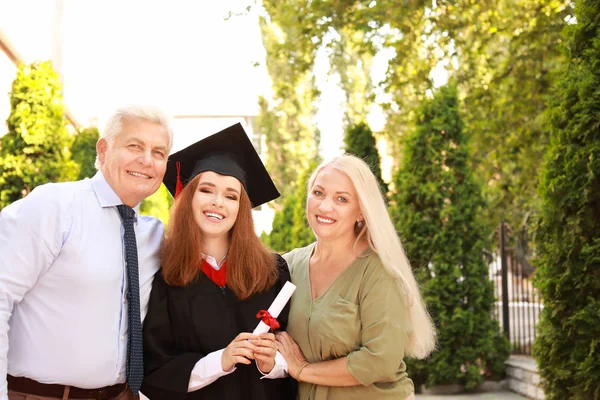 Happy young woman with diploma and her parents on graduation day — Stock Photo, Image
