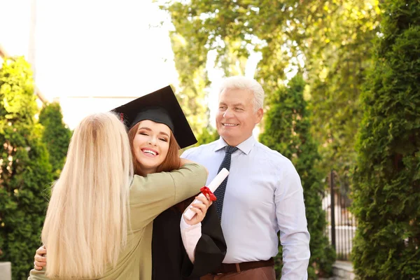 Feliz joven con diploma y sus padres en el día de la graduación — Foto de Stock