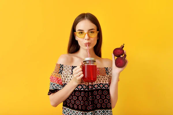 年轻女子喝健康的甜菜汁的颜色背景 — 图库照片