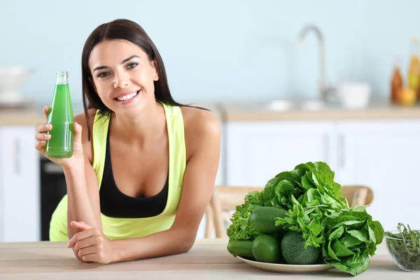 Mujer joven con jugo de verduras saludables en la cocina — Foto de Stock