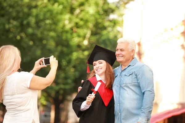 Mujer tomando fotos de su marido y su hija el día de la graduación — Foto de Stock