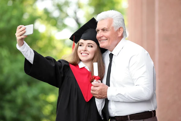 Lycklig ung kvinna med sin far tar Selfie på examensdagen — Stockfoto