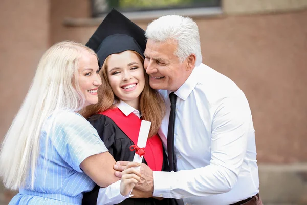 Feliz joven con sus padres en el día de la graduación — Foto de Stock