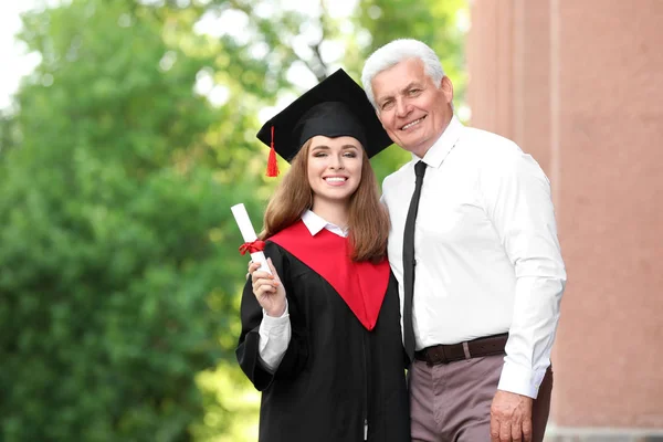 Щаслива молода жінка з батьком в день випуску — стокове фото