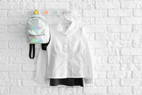 Elegante uniforme escolar con mochila colgada en la pared de ladrillo blanco — Foto de Stock