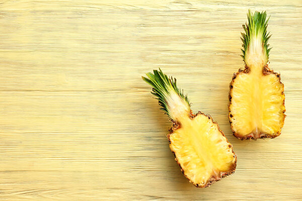 Halves of sweet pineapple on wooden background