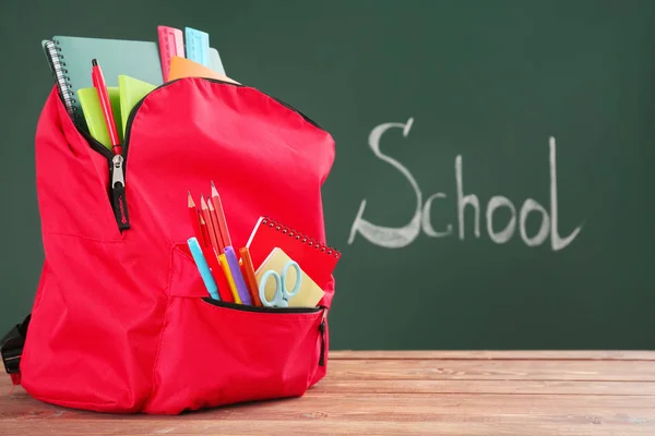 Rugzak met briefpapier op tafel in de klas — Stockfoto