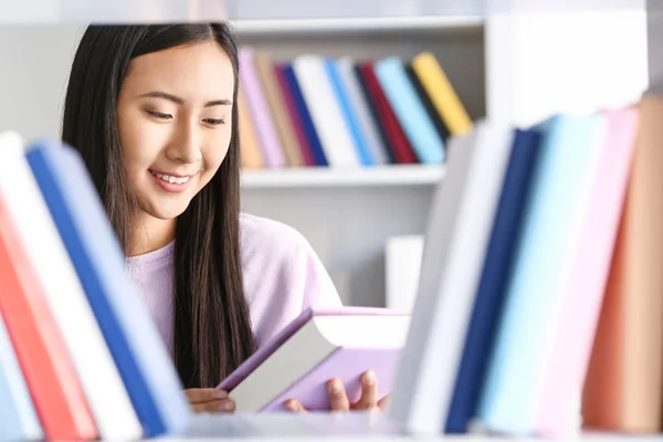Joven estudiante asiático eligiendo libros en la biblioteca —  Fotos de Stock