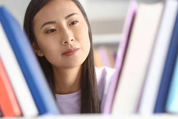 Joven estudiante asiático eligiendo libros en la biblioteca —  Fotos de Stock