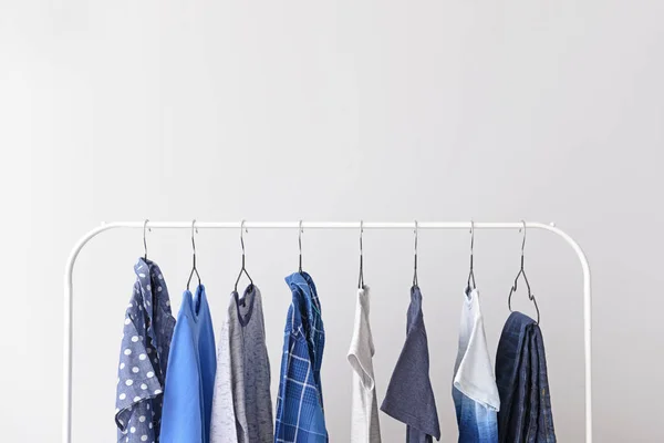 Stylish kid clothes hanging on rack against light background — Stock Photo, Image
