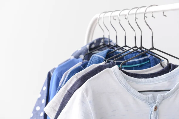 Stylish kid clothes hanging on rack against light background, closeup — Stock Photo, Image