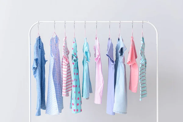 Stylish kid clothes hanging on rack against light background — Stock Photo, Image