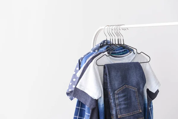 Elegante ropa de niño colgando en el estante contra el fondo claro — Foto de Stock